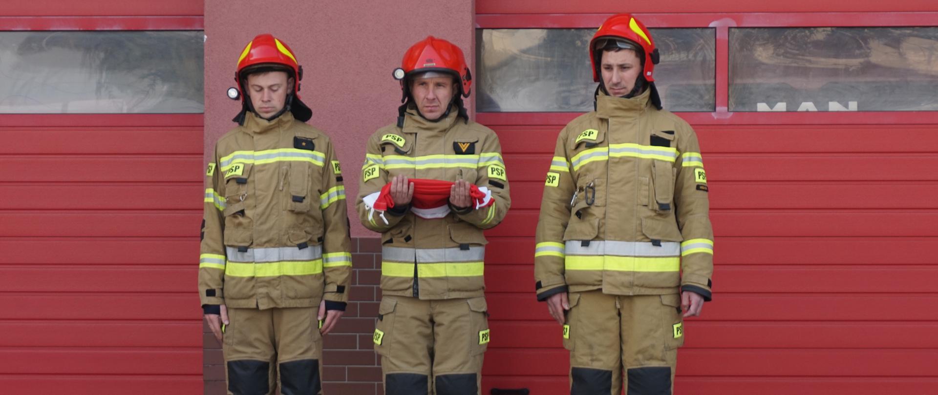 Poczet flagowy składający się z 3 strażaków w stroju bojowym.