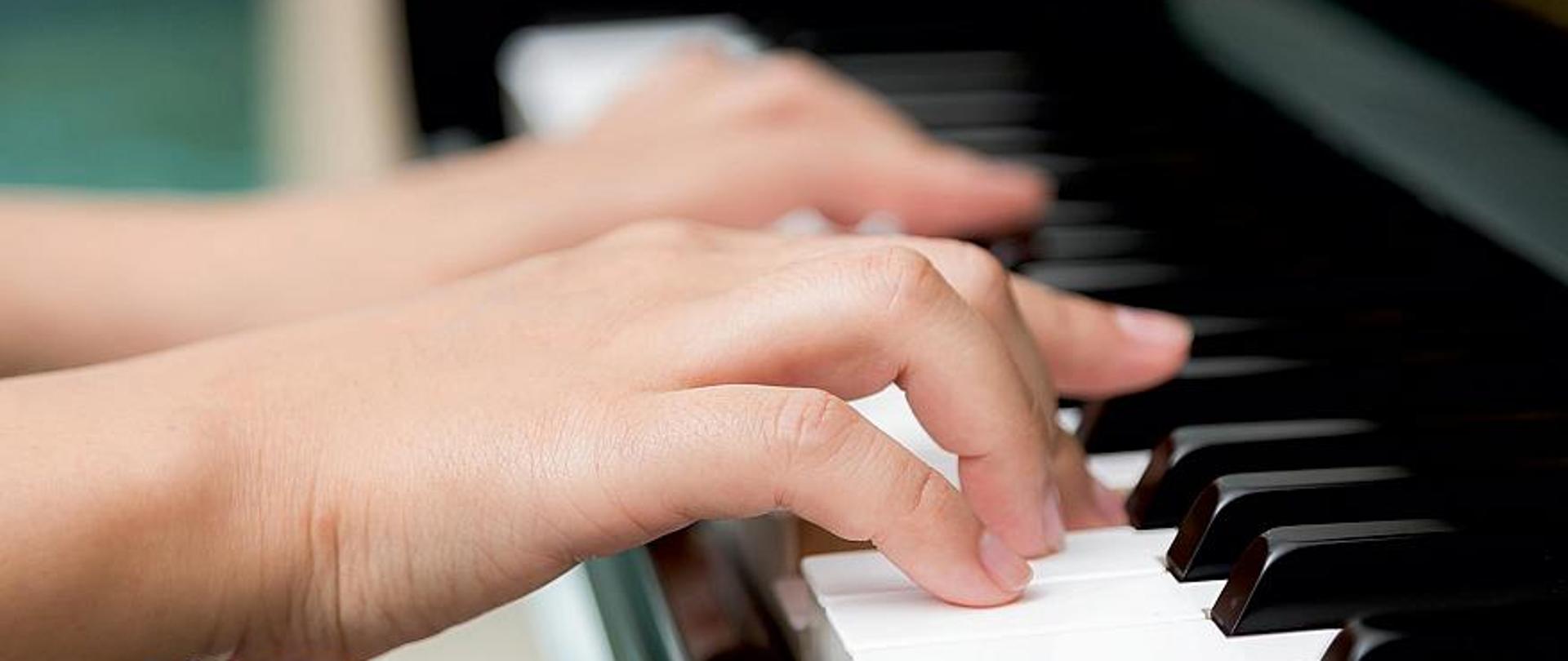 Plakat o kolorze granatowym informujący o II Szkolnym Konkursie Pianistycznym "Jak to grasz?". W części centralnej plakatu umieszczone jest zdjęcie rąk na klawiaturze fortepianu.