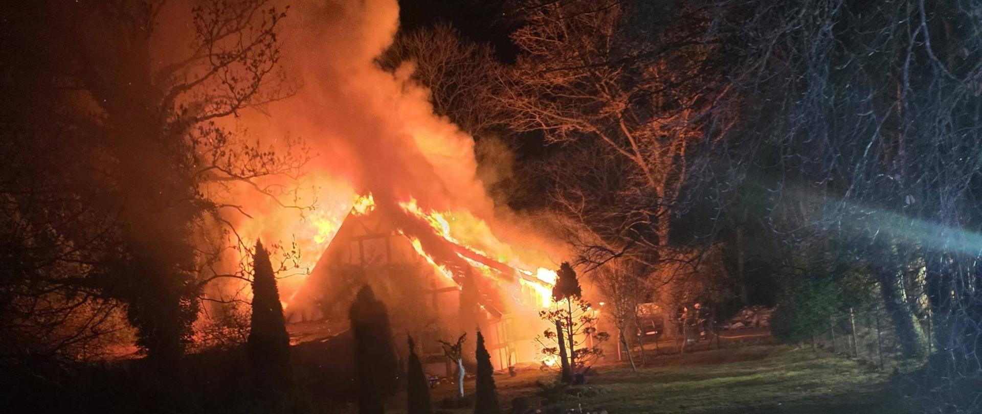 Zdjęcie przedstawia palący się dom.