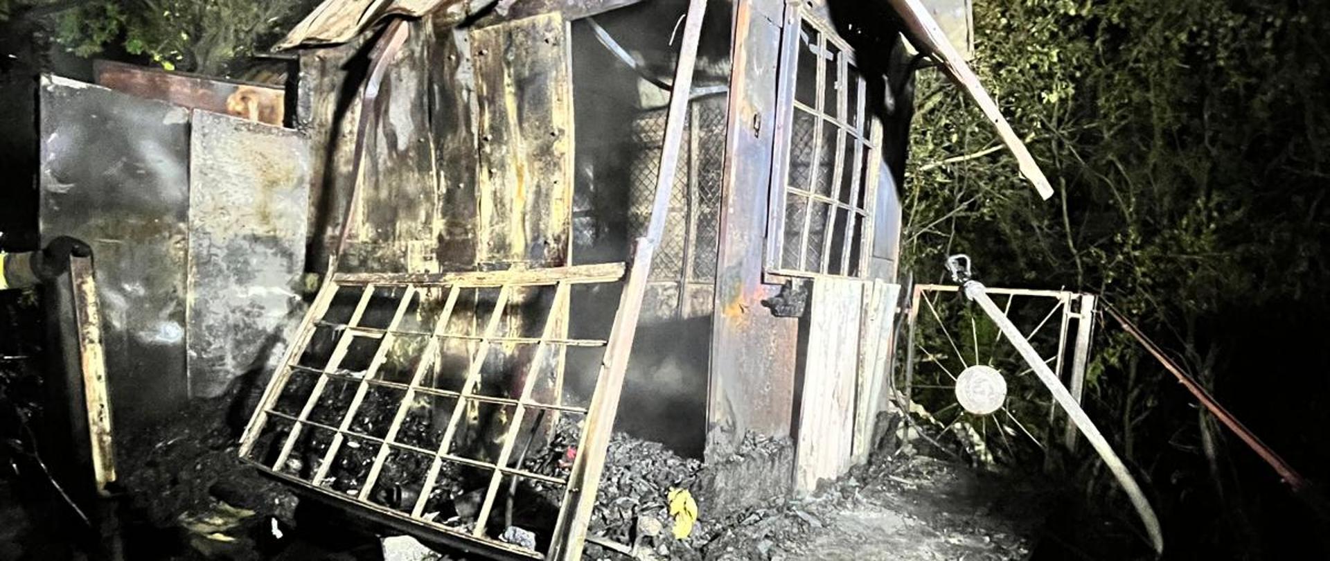 Zdjęcie przedstawia zniszczoną przez ogień altankę ogrodową.