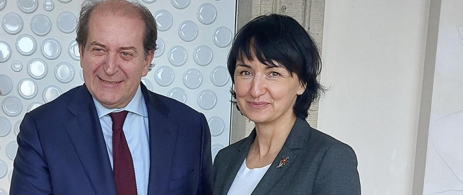 Kobieta i mężczyzna stoją na jasnym tle. 