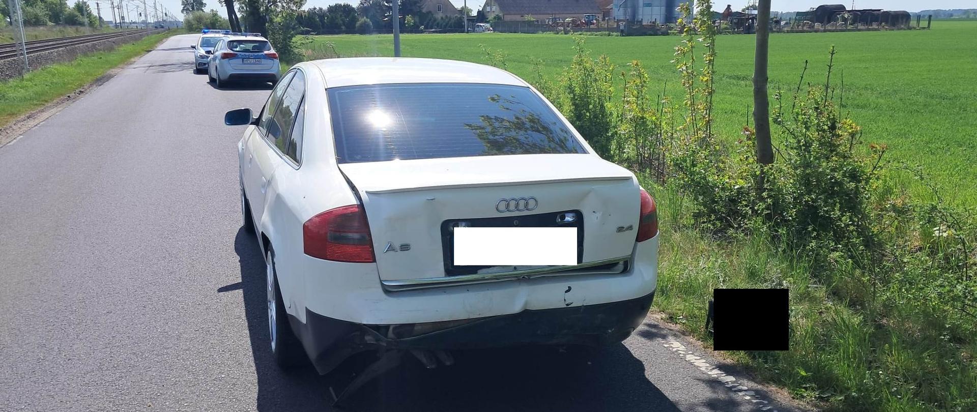 Biały pojazd na drodze, za nim policja
