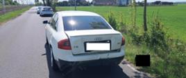 Biały pojazd na drodze, za nim policja