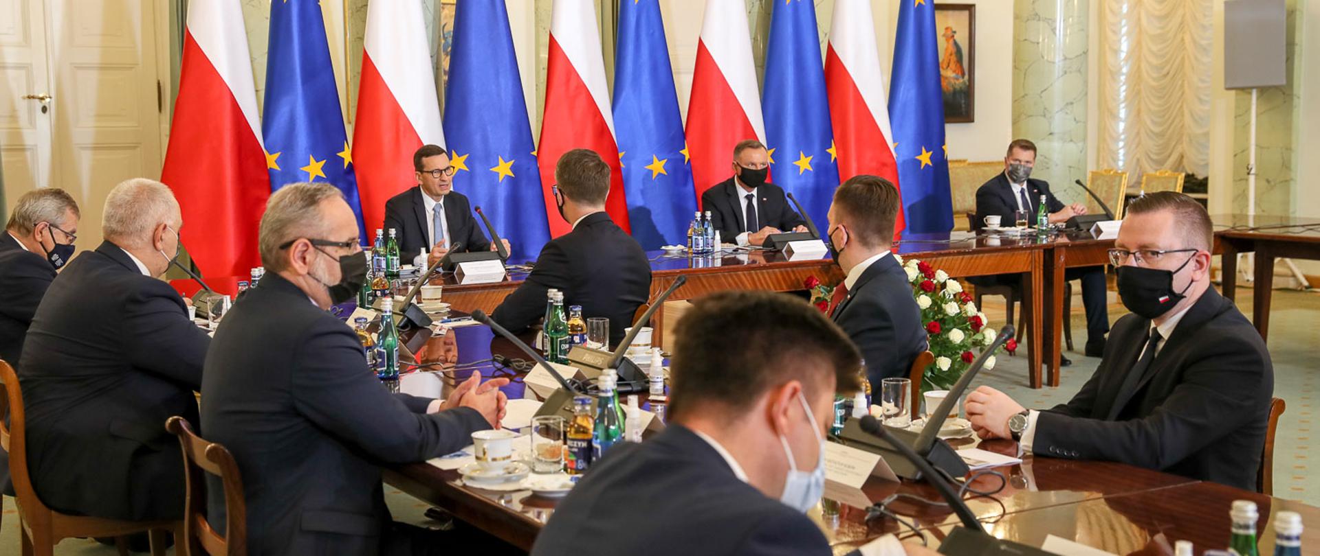 na zdjęciu widoczni uczestnicy rady gabinetowej, Prezydent Andrzej Duda, Premier Mateusz Morawiecki na tle flag biało czerwonych oraz europejskich