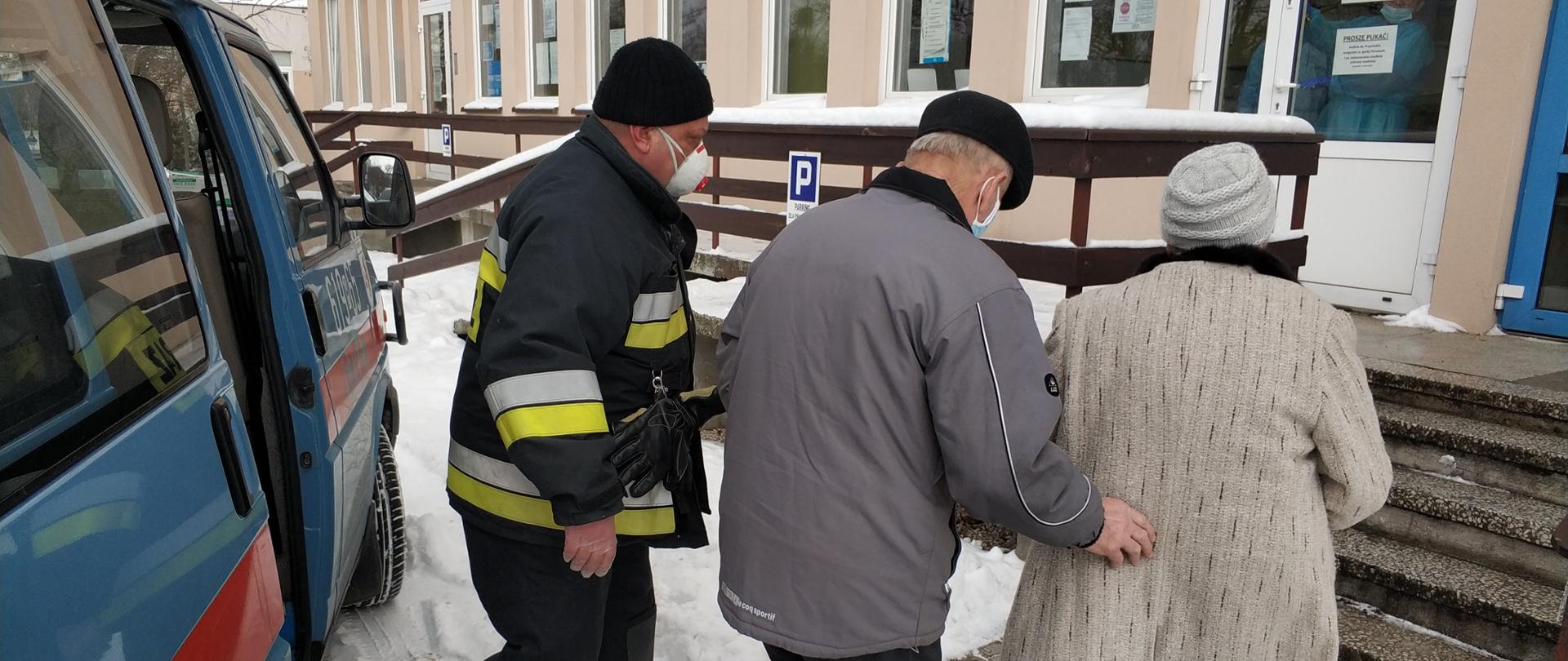 Strażak pomaga osobom w dotarciu do punktu szczepień