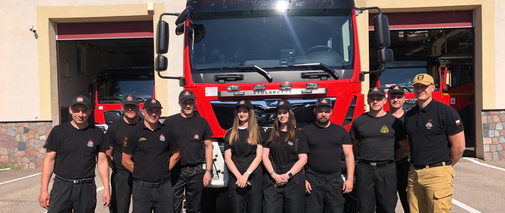 Strażacy na tle pojazdów