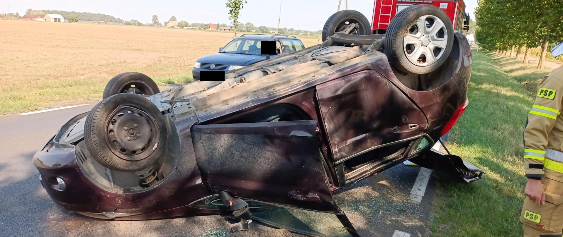 Widać samochód po dachowaniu na drodze, po lewej pole