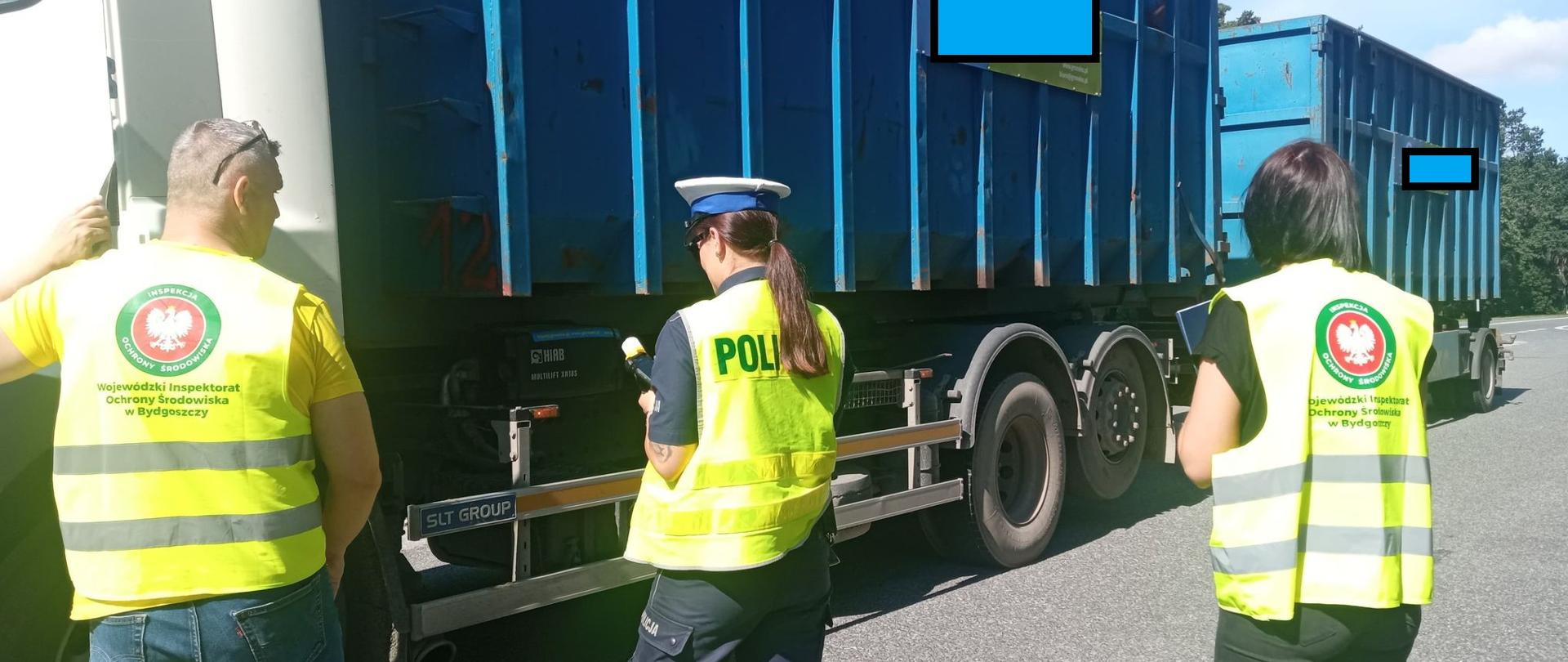 Policjantka wraz z pracownikami Inspekcji Ochrony Środowiska kontroluje pojazd