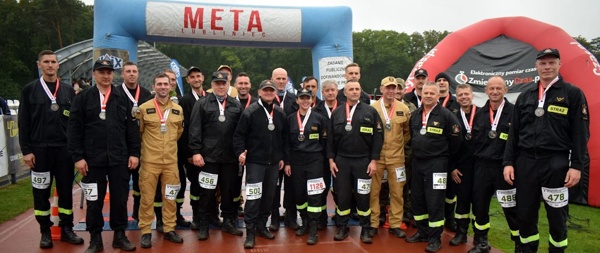 Grupa uczestników mistrzostw na tle baneru z napisem meta 