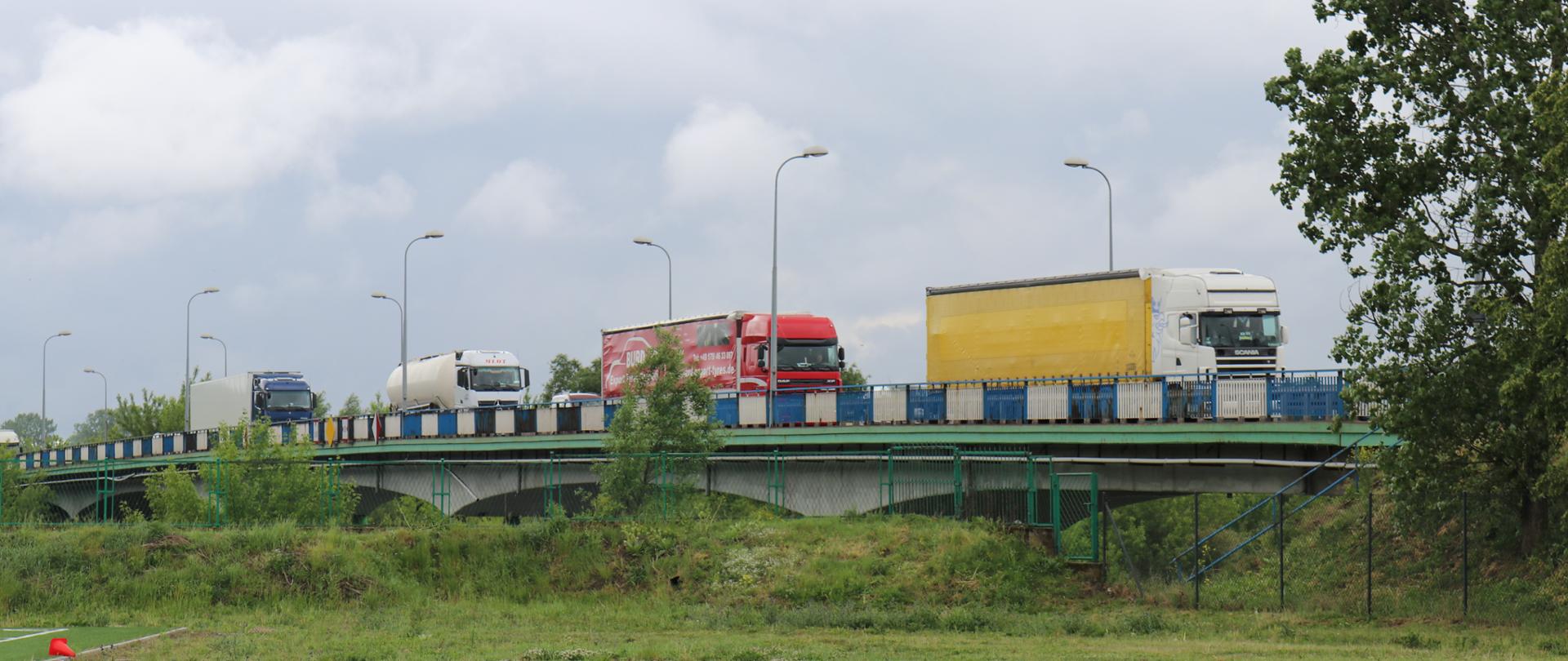Cztery ciężarówki tzw. TIR-y jadą jedna za drugą po starym moście nad Narwią, w Łomży 