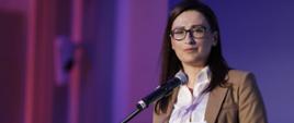 Wiceminister klimatu i środowiska Małgorzata Golińska stoi przy mównicy i przemawia do mikrofonu