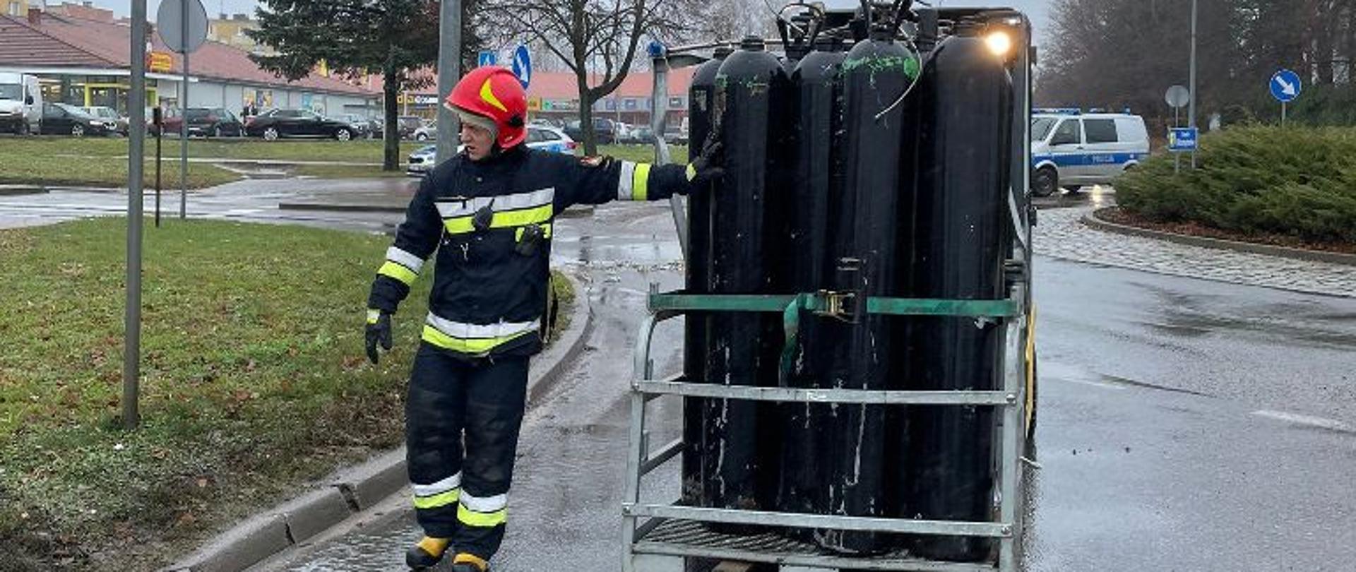 Wózek widłowy przewozi pojemnik z butlami.