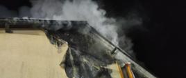Zdjęcie przedstawia strażaków gaszących pożar domu w Laskowie.
W tle budynki.
