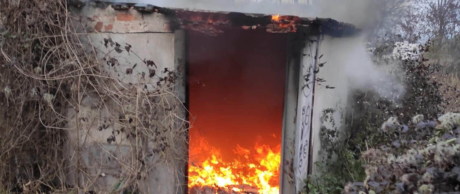 Pomieszczenie budynku gospodarczego całego w ogniu. Budynek ten przylegał do drugiego. 