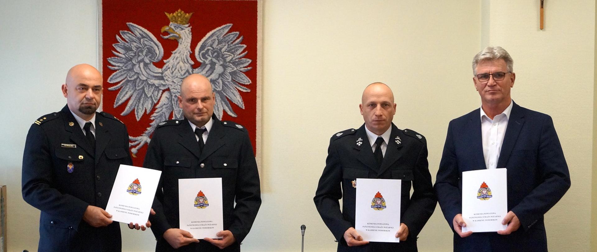 Zdjęcie przedstawia przedstawicieli straży państwowej i osp oraz władze miasta trzymających podpisane dokumenty.