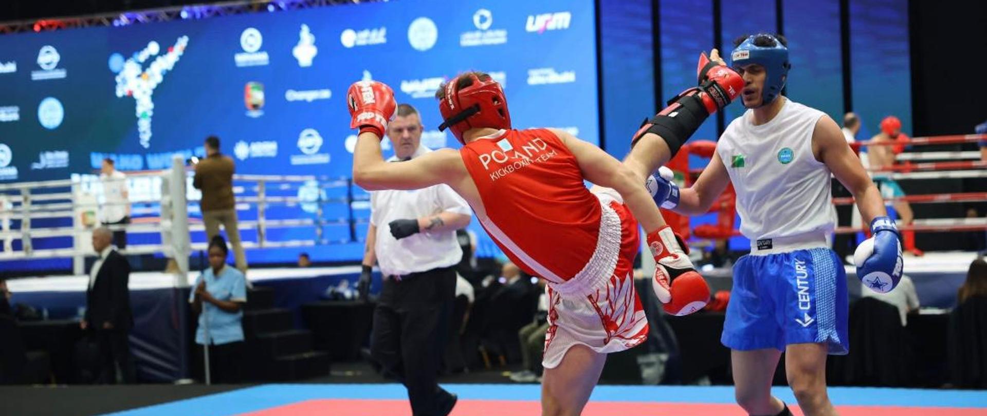 Zdjęcie przedstawia walkę dwóch zawodników podczas zawodów w kickboxingu. 