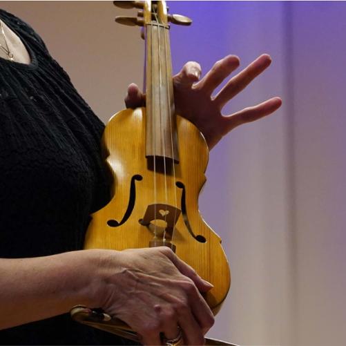 Zdjęcie przedstawia skrzypce barokowe trzymane w rękach skrzypaczki