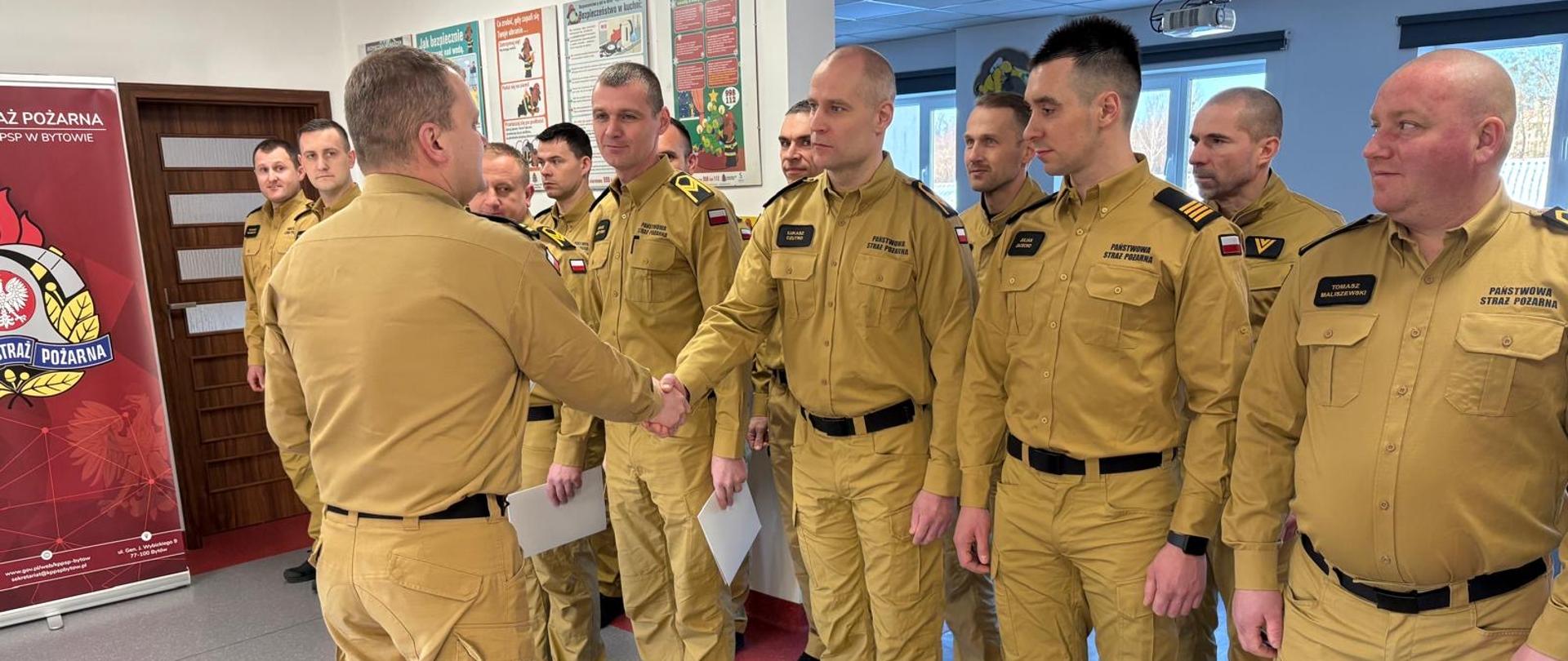 Funkcjonariusze w umundurowaniu koloru żółtego podczas wręczania decyzji. 