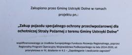 Tablica informacyjna na białym tle napis "zakup pojazdu specjalnego ochrony przeciwpożarowej dla osp z terenu gminy ustrzyki dolne" na dole tablicy wymienieni sponsorzy.