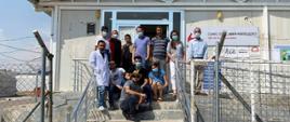 grupa lekarzy i pacjentów przed przychodnią lekarską dla wewnętrznie przesiedlonych Irakijczyków i społeczności przyjmującej w obozie w Irackim Kurdystanie 