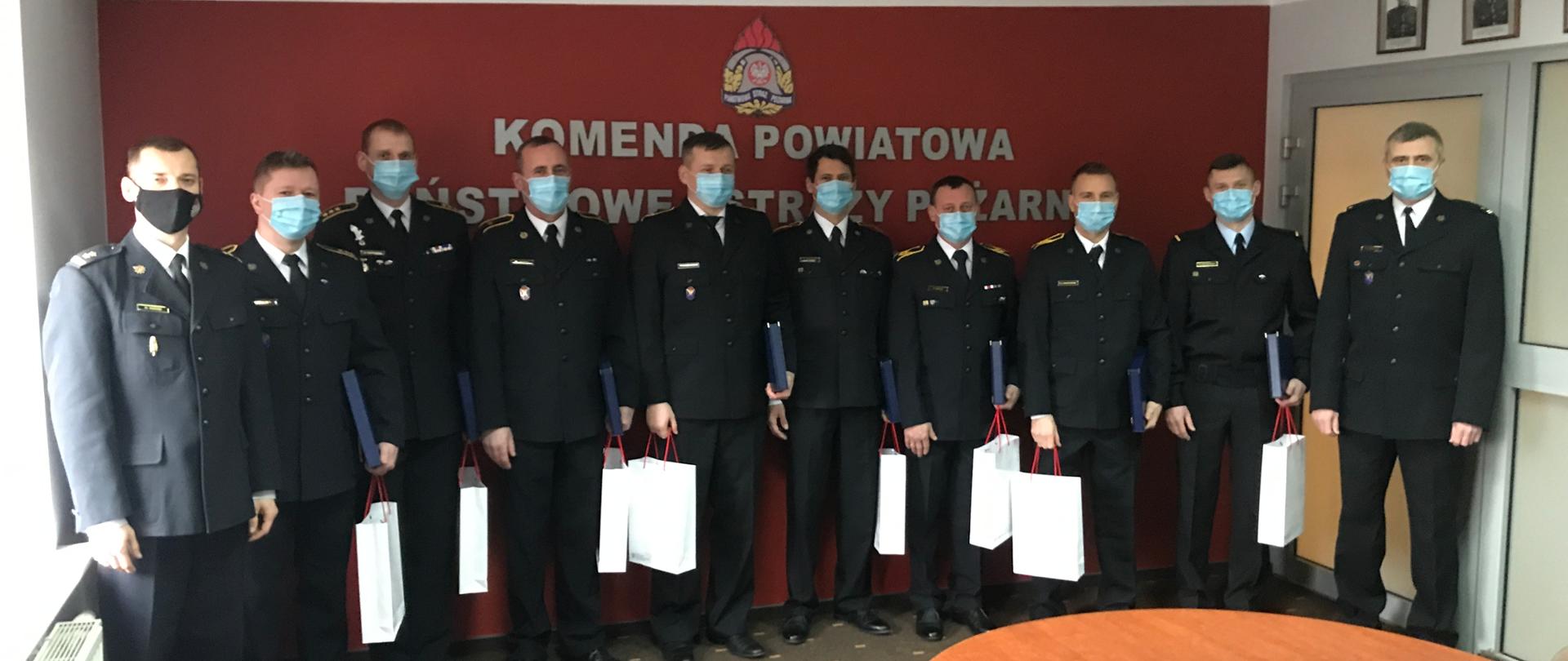 Strażacy stojący w rzędzie z wręczonymi nagrodami