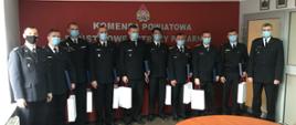 Strażacy stojący w rzędzie z wręczonymi nagrodami
