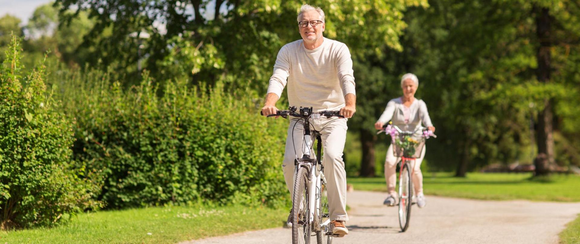 active old age, people and lifestyle concept - happy senior couple riding bicycles at summer park