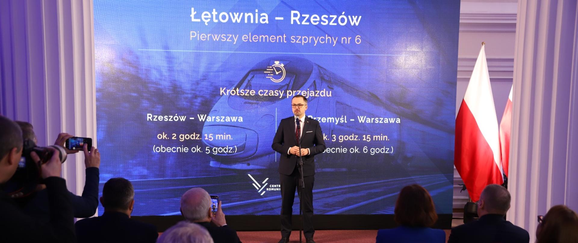 Wiceminister Marcin Horała stoi na podeście i mówi do mikrofonu.