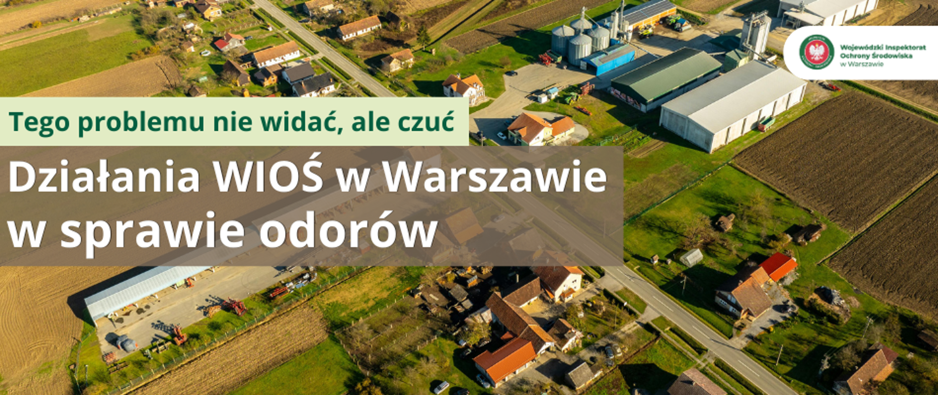 Plansza z napisem "Tego problemu nie widać, ale czuć - Działania WIOŚ w Warszawie w sprawie odorów". W tle widok wsi z lotu ptaka, budynki mieszkalne, gospodarskie i kilka hal.