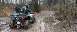 Zdjęcie przedstawia strażaka poruszającego się pojazdem terenowym drogą leśną po grząskim terenie. 