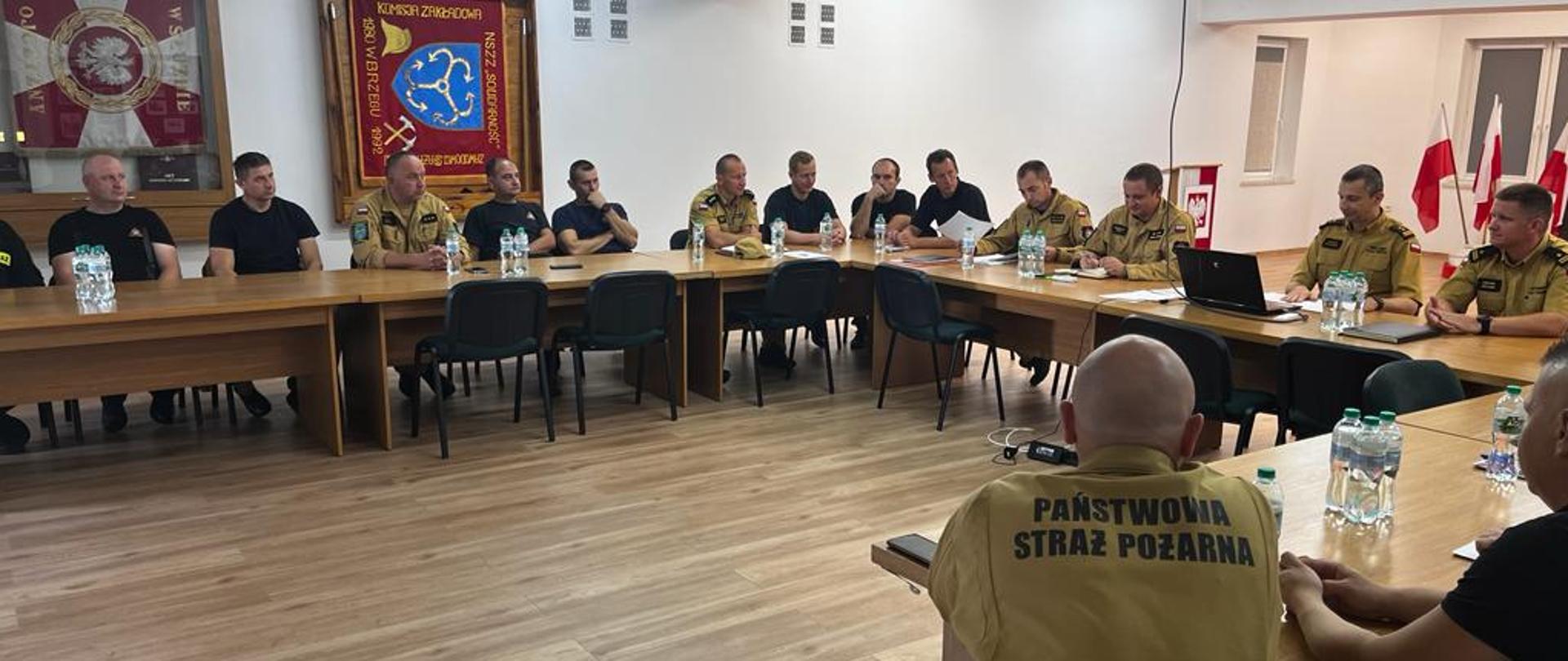 Kadra dowódcza KP PSP w Brzegu oraz obsada Stanowiska Kierowania Komendanta Powiatowego PSP w Brzegu podczas odprawy operacyjnej.