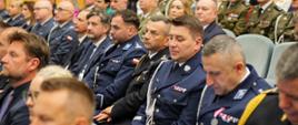 funkcjonariusze Policji oraz PSP w tym wielkopolski komendant wojewódzki psp siedzą na dużej auli podczas uroczystości 