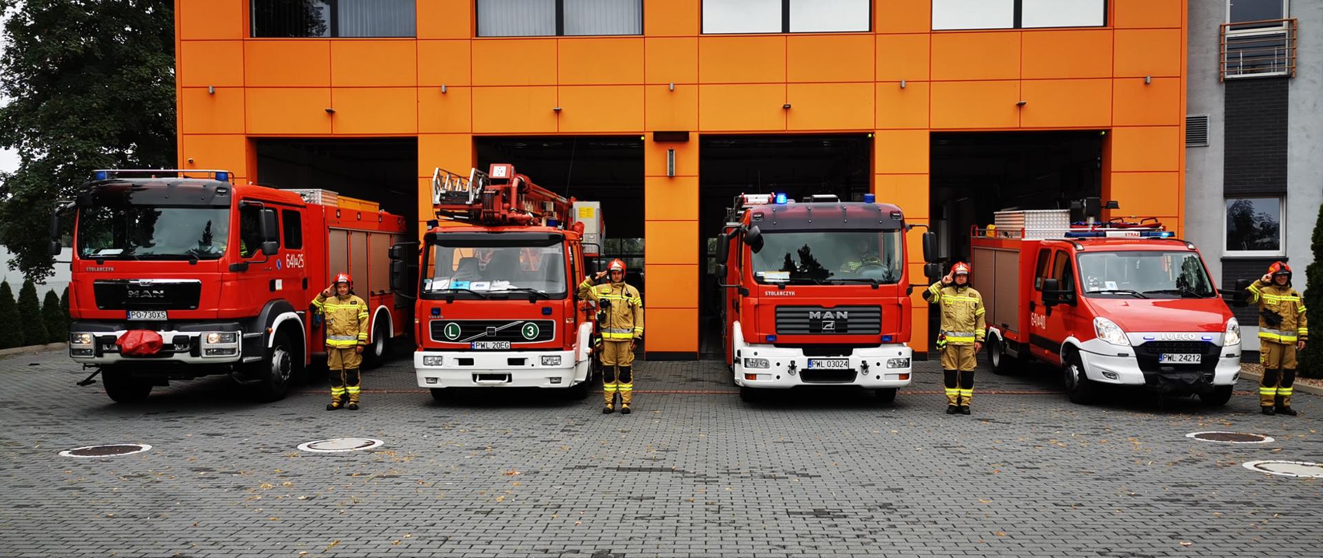 Budynek jednostki, przed budynkiem samochody i strażacy, strażacy oddają hołd