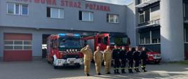 Zdjęcie przedstawia strażaków stojących w szyku przed garażem podczas oddania hołdu bohaterom powstania warszawskiego. Za nimi stoją samochody strażackie.