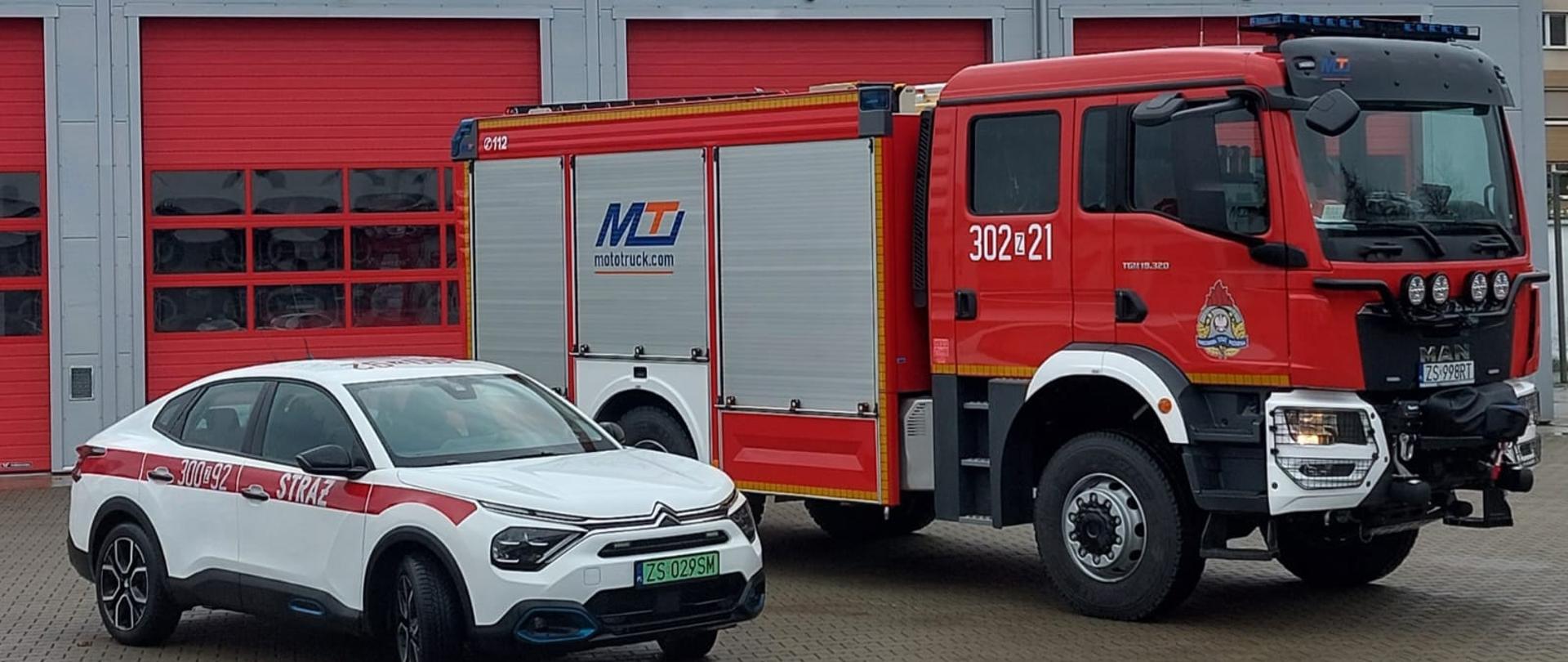 Dwa samochody na placu wewnętrznym przed garażem.