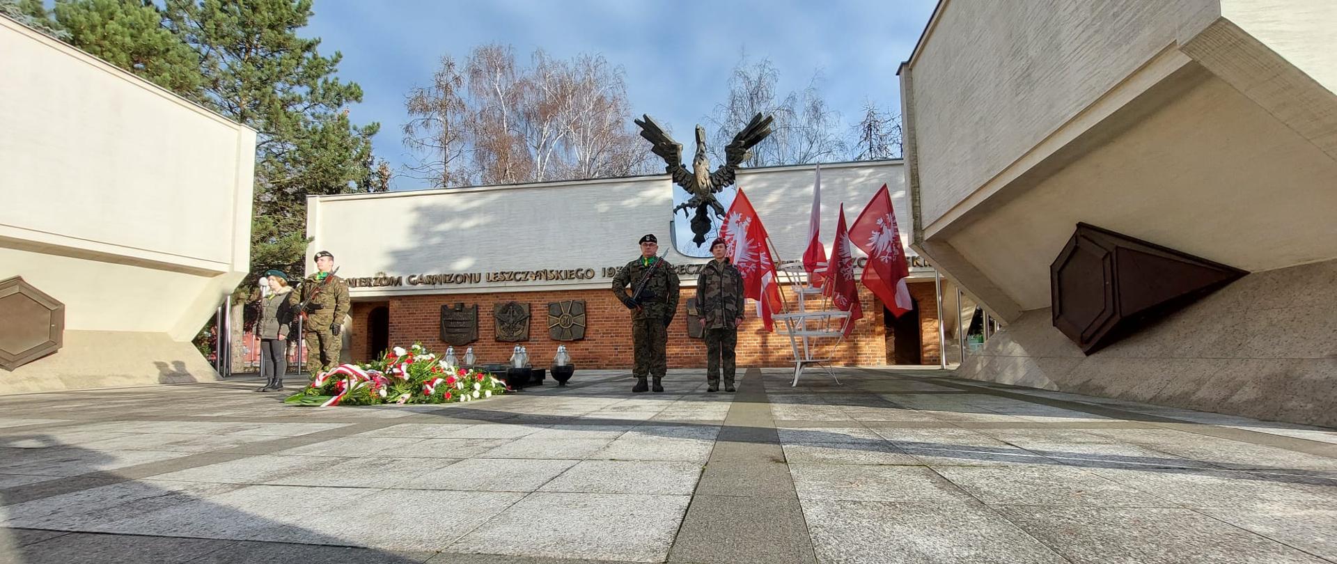 Żołnierze pełnią wartę przed pomnikiem.