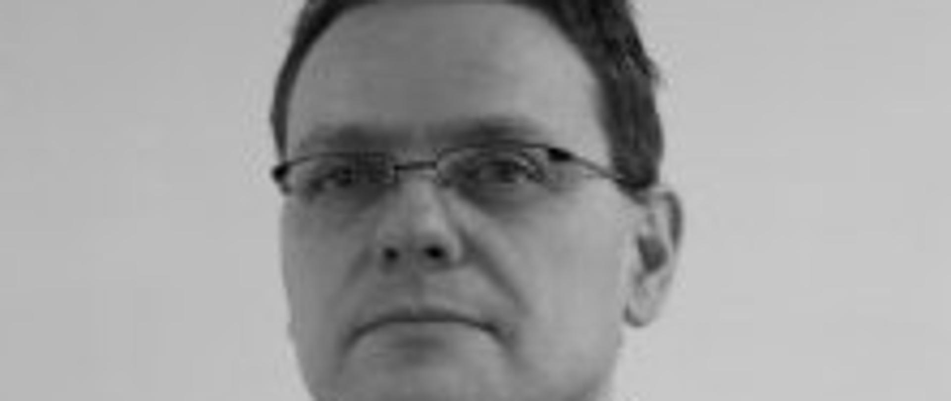 czarno-białe zdjęcie strażaka w okularach w mundurze w białej koszuli z krawatem
