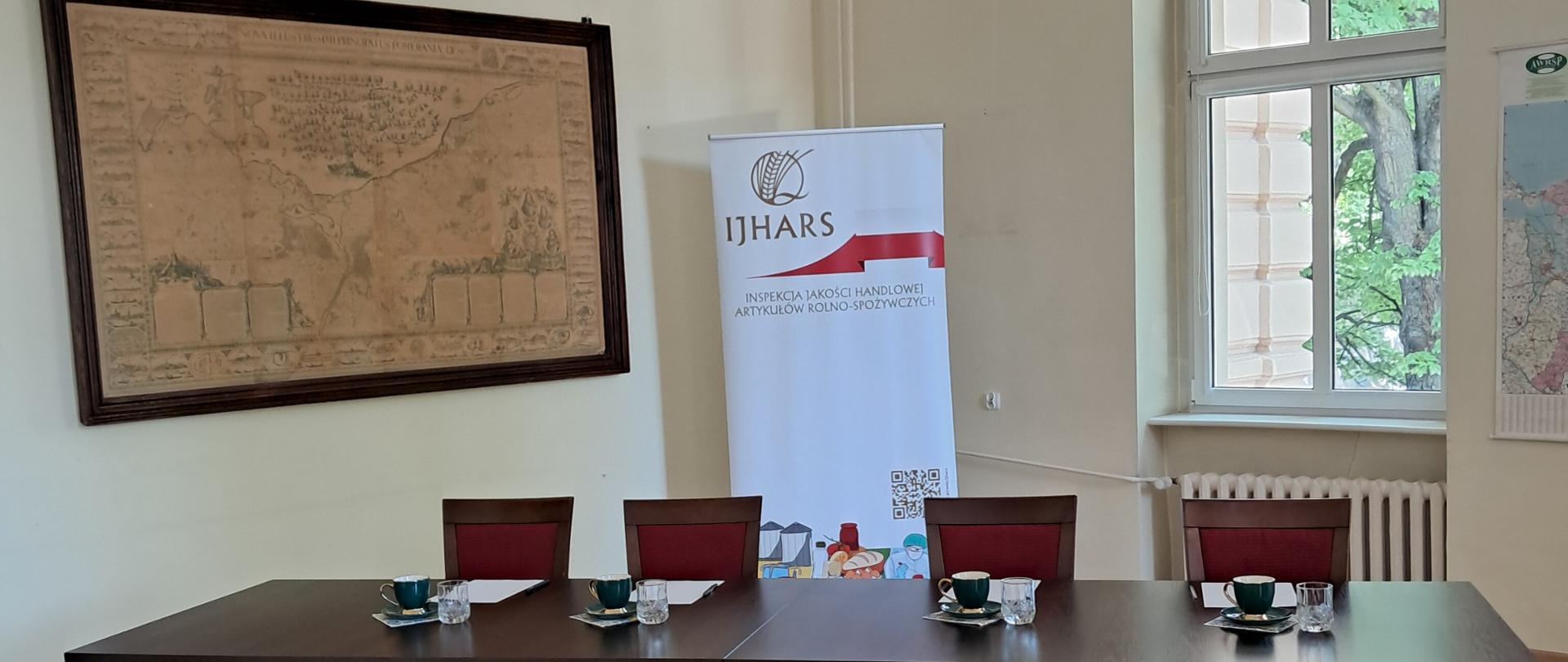 stoły i krzesła członków komisji przed egzaminem, w tle logo IJHARS