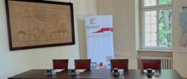 stoły i krzesła członków komisji przed egzaminem, w tle logo IJHARS