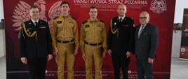 Zastępca śląskiego komendanta wojewódzkiego, komendant powiatowy oraz starosta na wspólnym zdjęciu na tle baneru państwowej straży pożarnej na wspólnym zdjęciu z nowoprzyjętymi strażakami