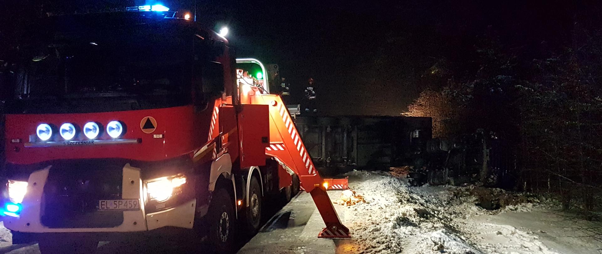 Na zdjęciu widoczne działania ratownicze polegające na podnoszeniu przewróconego na drogę samochodu ciężarowego.