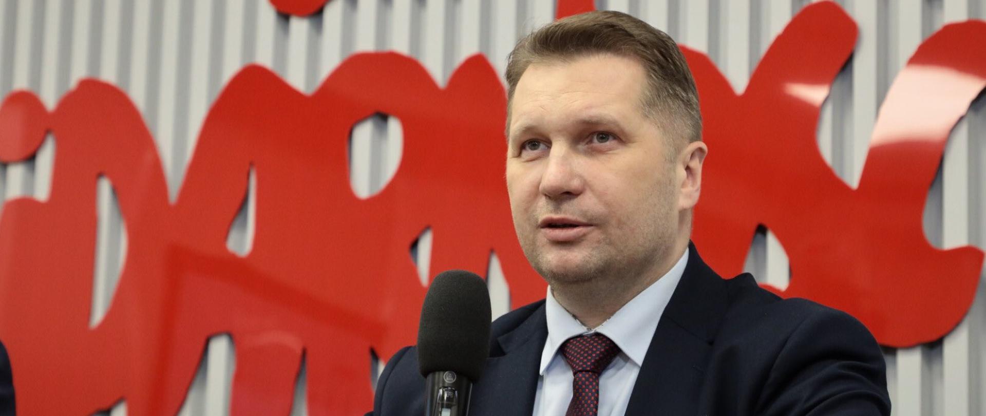Minister Przemysław Czarnek siedzi za stołem podczas debaty związanej z Solidarnością i przemawia do mikrofonu
