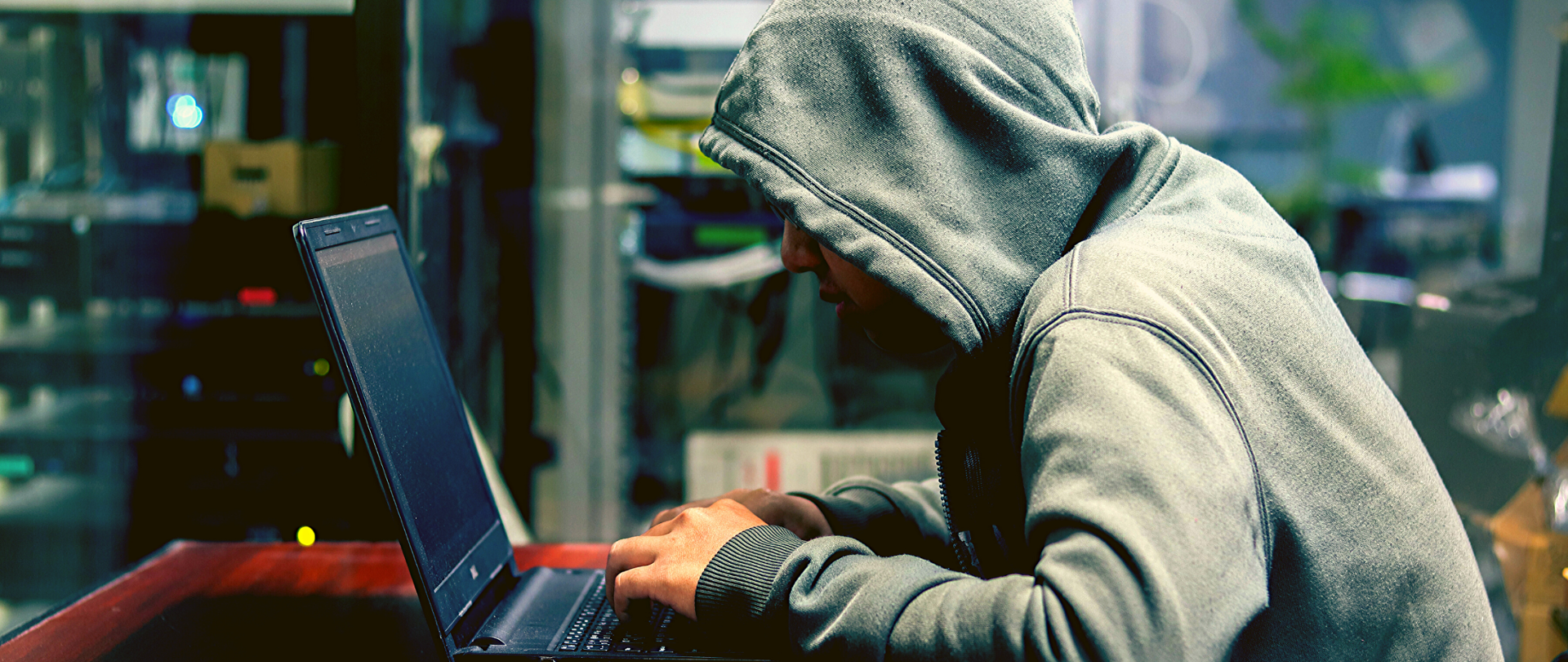 Mężczyzna w bluzie z kapturem siedzi przy otwartym laptopie