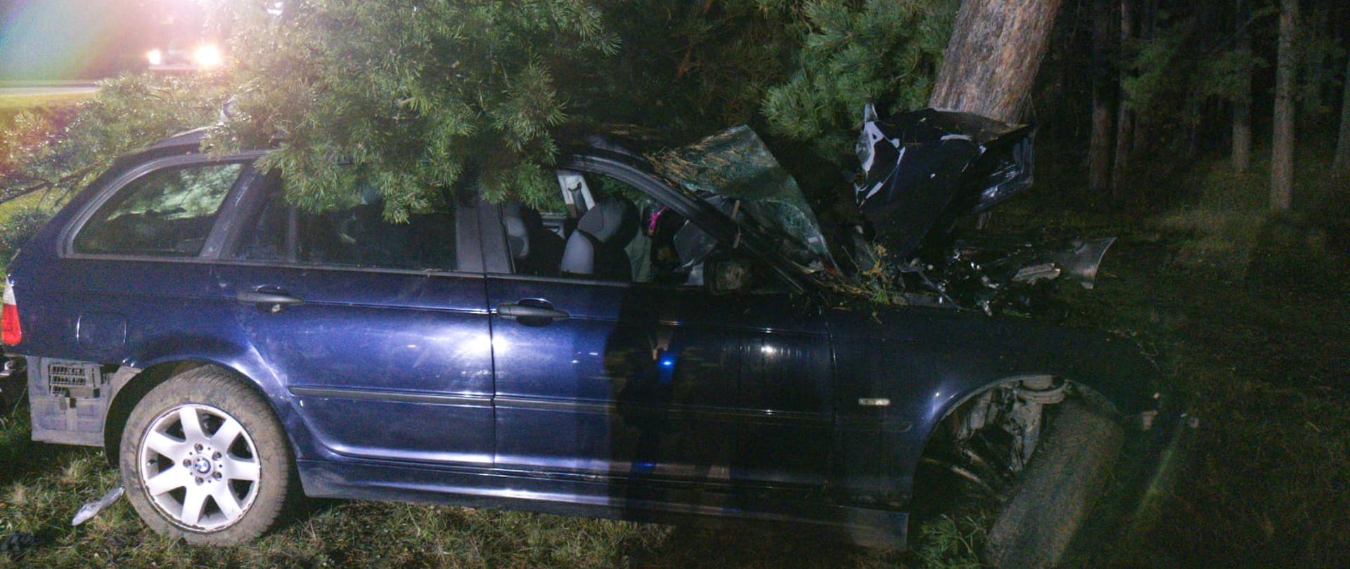 Wypadek drogowy. Na zdjęciu widać samochód osobowy marki BMW po uderzeniu czołowym w przydrożne drzewo. 