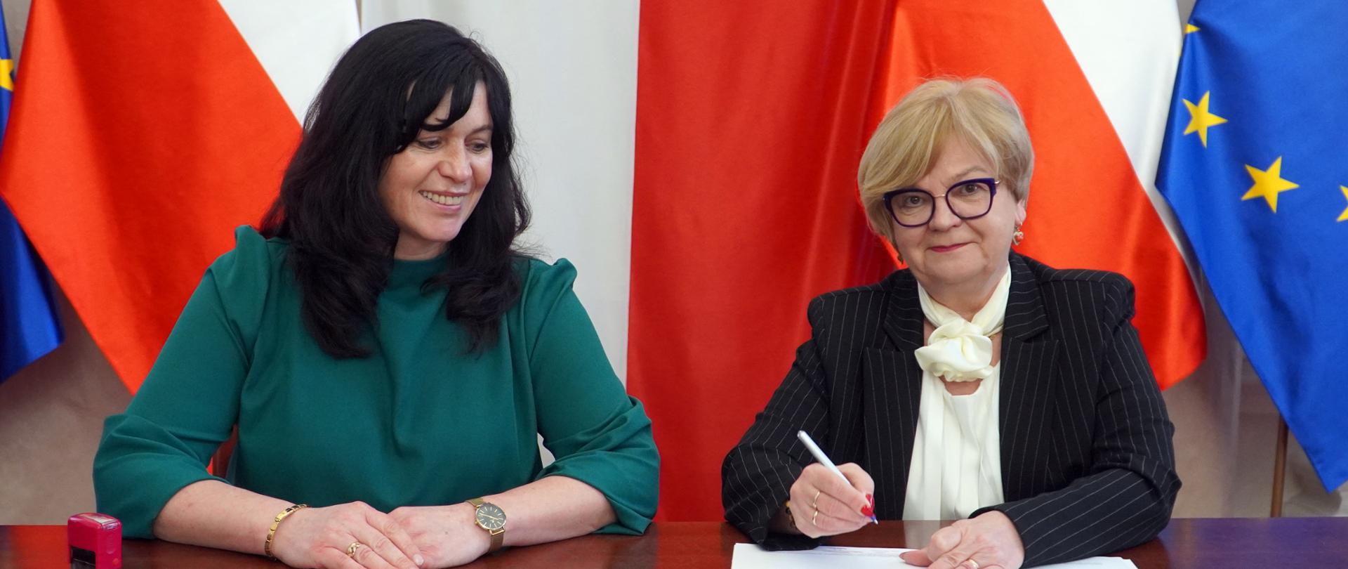 Zdjęcie przedstawia dwie osoby podpisujące umowę