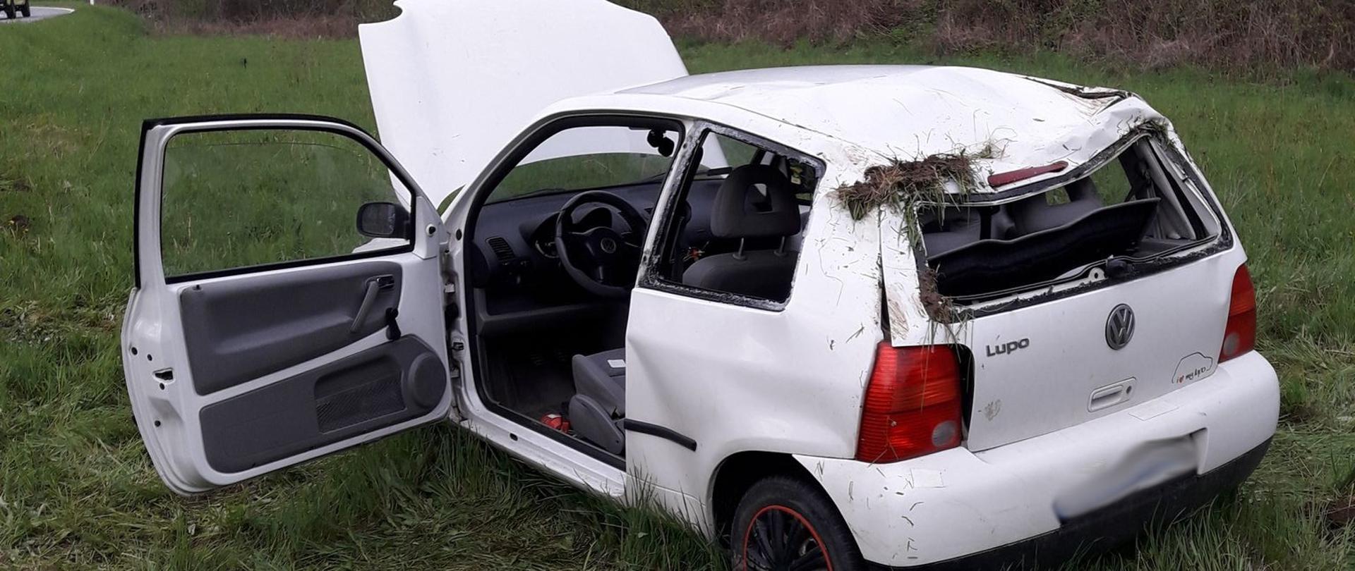 Uszkodzony samochód koloru białego stoi poza drogą