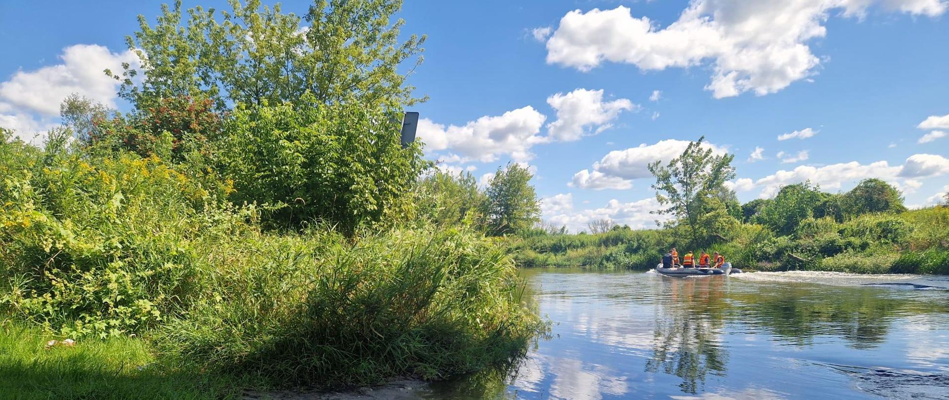 Strażacy oraz policjanci w pontonie płyną rzeką Nida.