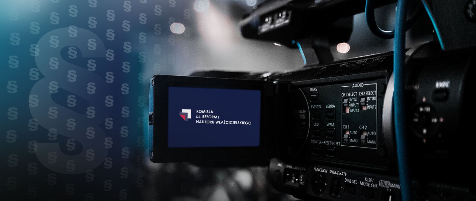 Kamera, na jej ekranie logotyp Komisji ds. Reformy Nadzoru Właścicielskiego. Na tle znaki paragrafu