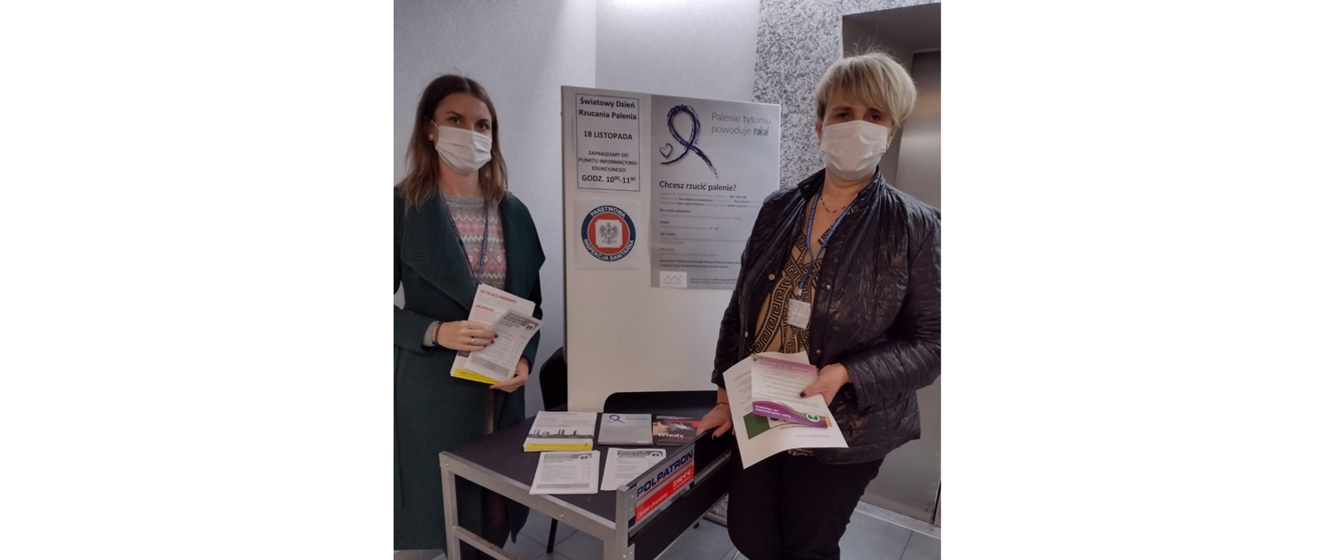 Pracownicy Państwowej Inspekcji Sanitarnej przy stoliku z ulotkami oaz tablicy informacyjnej