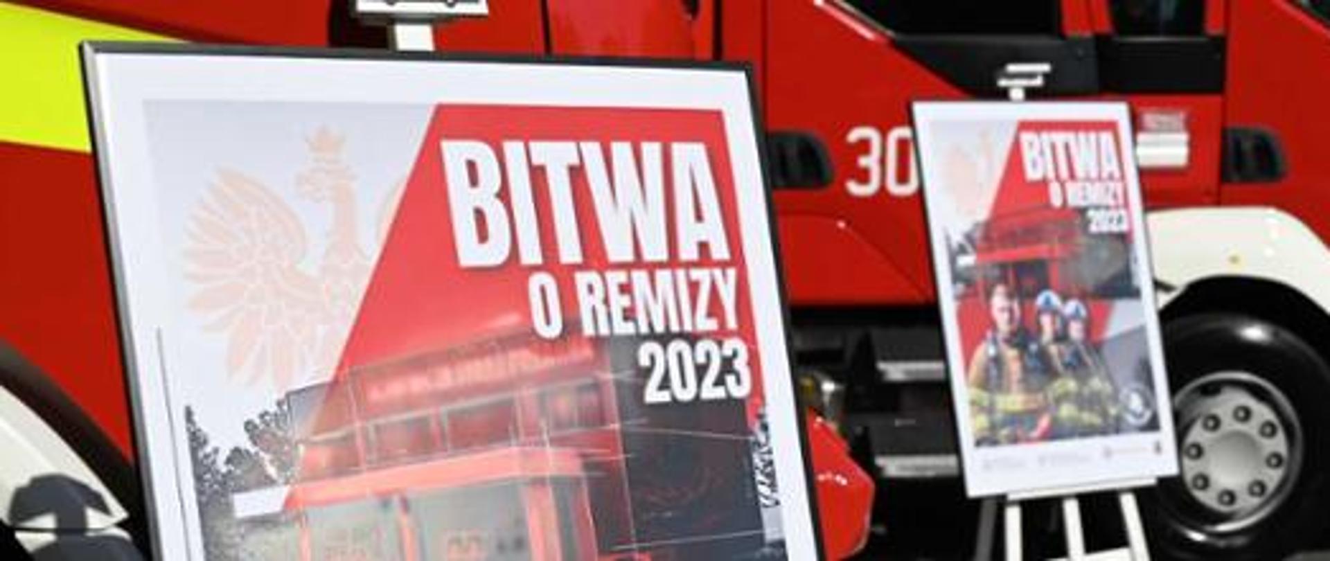 Dwa plakaty promocyjne akcji Bitwa o Remizy 2023 na tle dwóch pojazdów pożarniczych